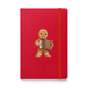 Balkan Christmas hardcover notebook with gingerbread accordion character on red cover — festive Balkan-inspired stationery by Balkanish
