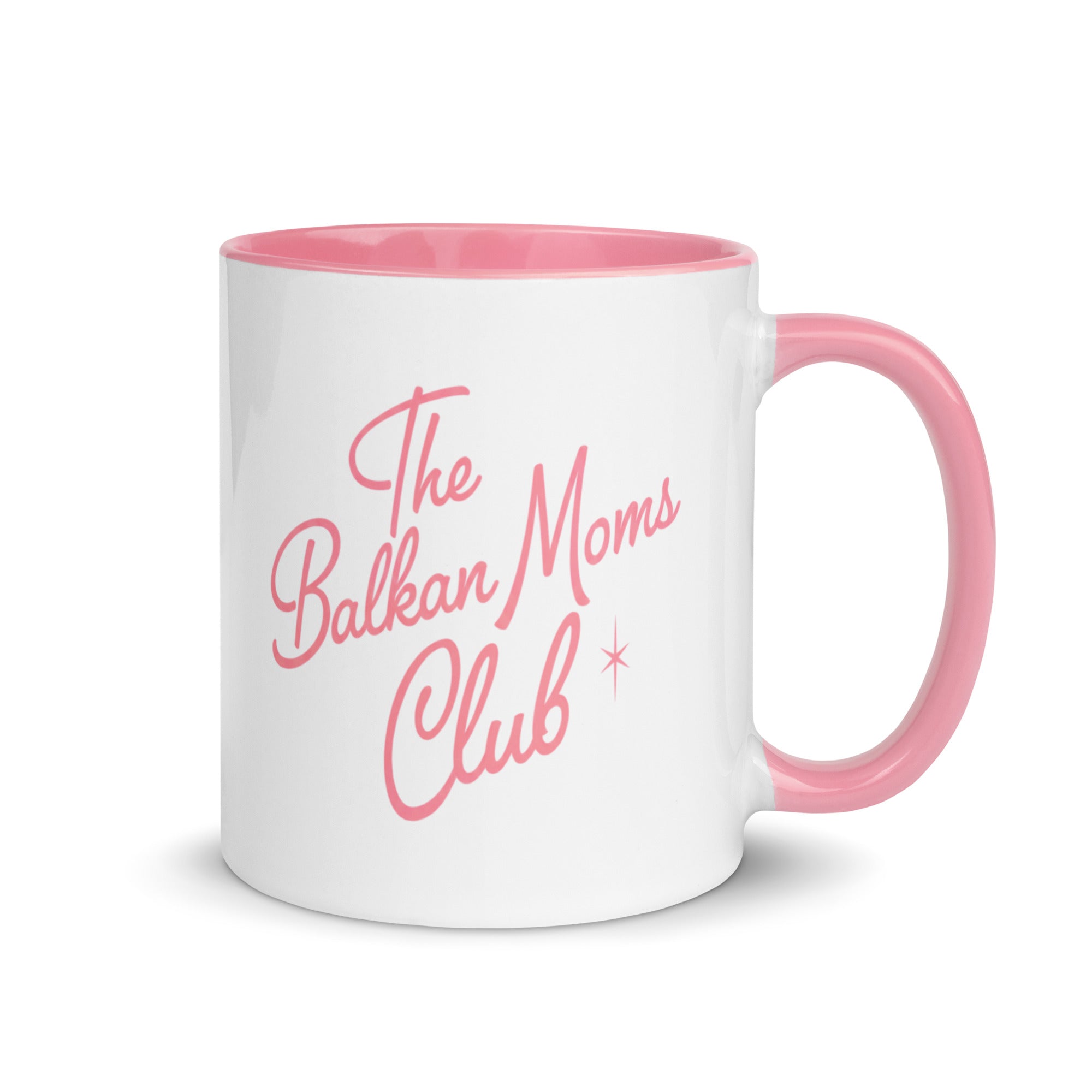 White mug with pink handle reading “The Balkan Moms Club.”