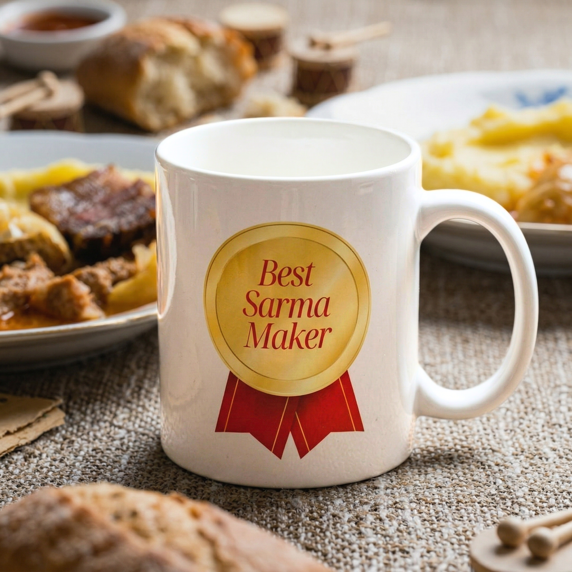 White mug with 'Best Sarma Maker' design on a table with food in the background