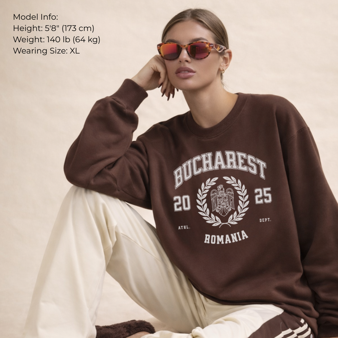 Woman wearing a brown sweatshirt with 'Bucharest 2025 Romania' text, sitting on a beige background.