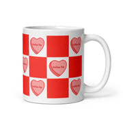 White mug with red and white checkered pattern and heart designs reading “Volim te.”