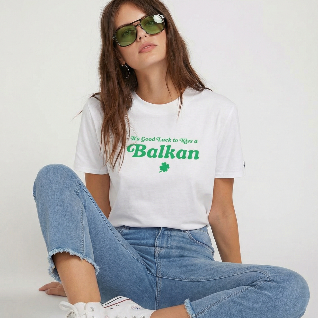 it's good luck to kiss a Balkan t-shirt in white on female model sitting on ground