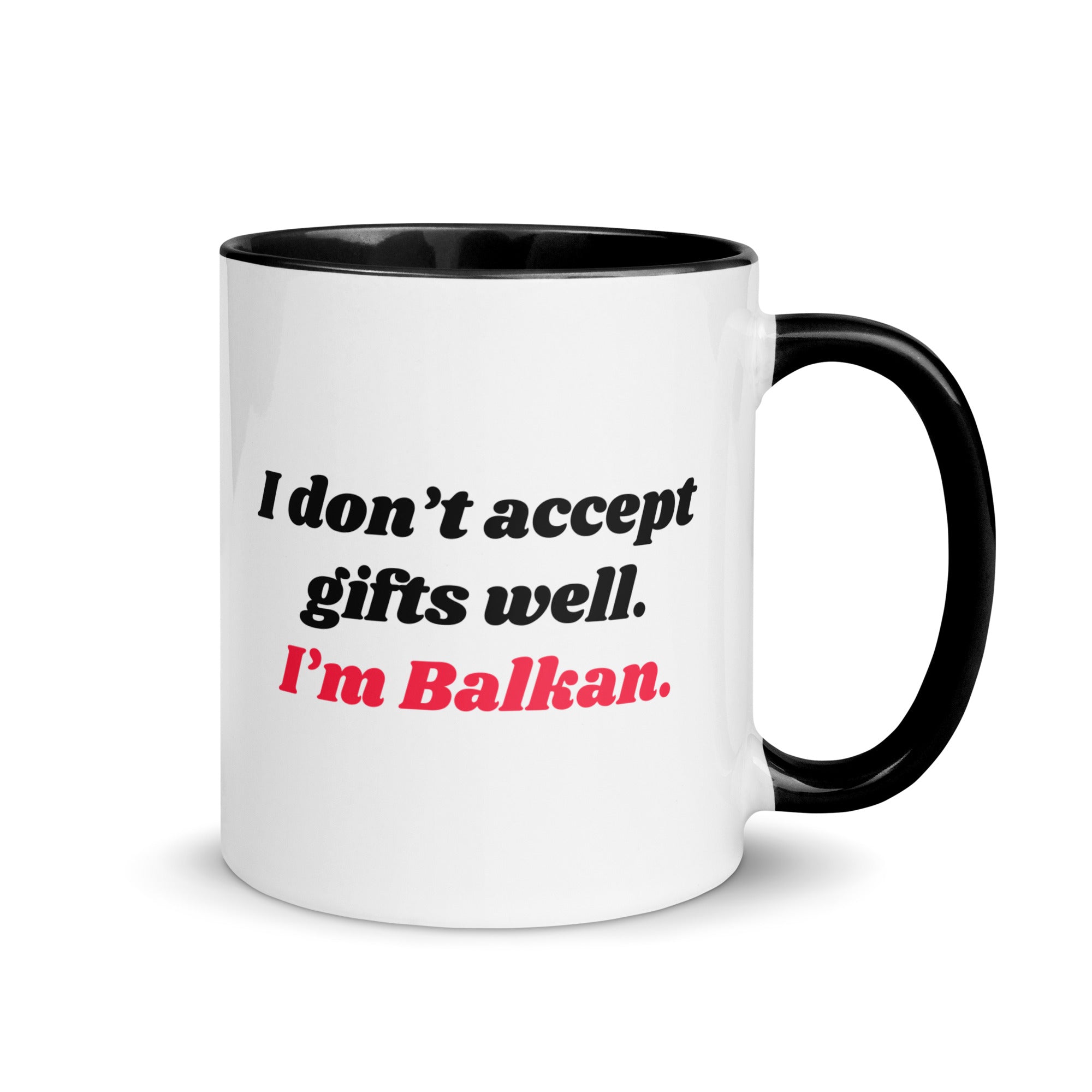 White mug with black handle reading “I don’t accept gifts well. I’m Balkan.”
