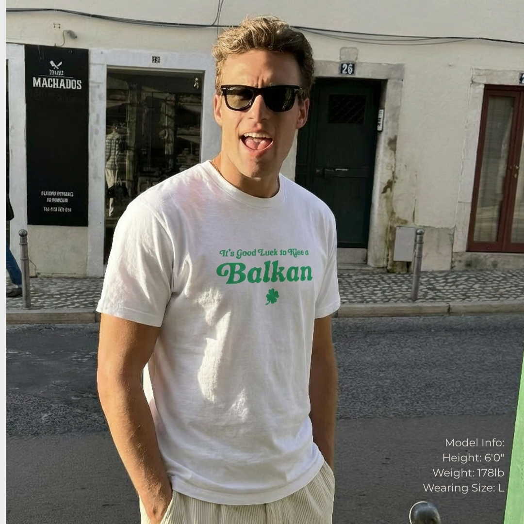 candid photo of a young man wearing sunglasses and "it's good luck to kiss a Balkan" t-shirt in white