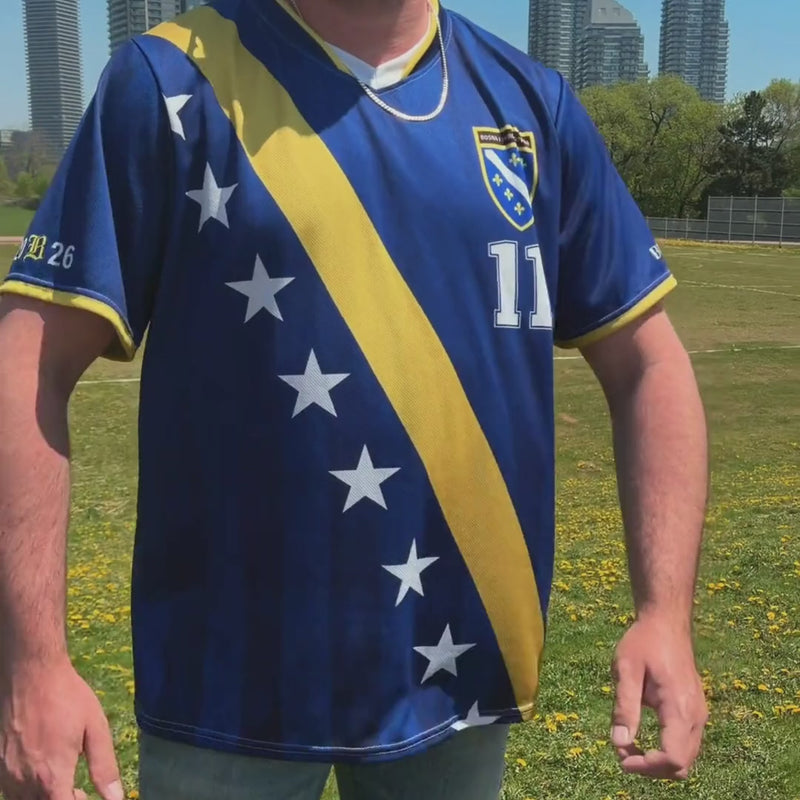 Model wearing the limited edition Bosna Je Stigla 2026 football jersey inspired by Bosnia and Herzegovina, featuring blue and gold details, diaspora fanwear styling, and streetwear-inspired match day design.