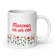 White mug with red text reading “Muncesc ca un cal” above colorful flowers.