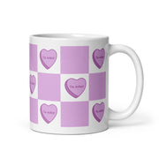 White mug with lavender checkered pattern and heart designs reading “Te ador.”